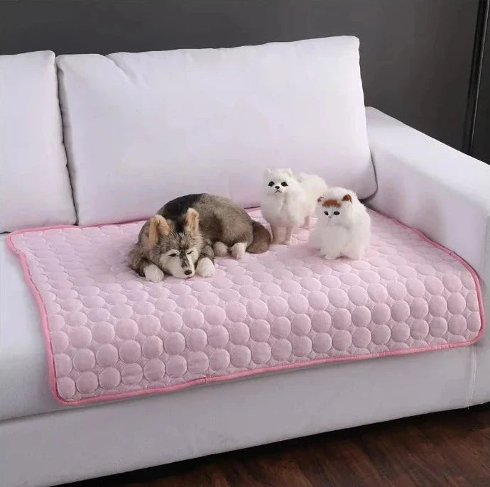 Pink quilted dog cooling mat on a sofa with pets